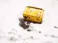 Fallen turned over yellow grit box salt outside snow storm Royalty Free Stock Photo
