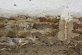 Fallen white platers reveals old mud brick on a country house.