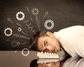 Cog wheels springing from a fed up and tired businessman`s head resting on laptop keyboard