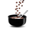Falling chocolate cereal balls in milk in a black bowl isolated on a white background Royalty Free Stock Photo