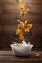 Falling corn flakes with milk splash on wood