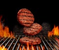 Falling down beef cutlets for burgers. Meat roasted on metal barbecue BBQ grill with flaming fire and ember charcoal on Royalty Free Stock Photo