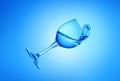 Falling down glass of water on a blue background. Royalty Free Stock Photo