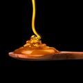 Falling and flowing honey on a wooden spoon isolated on black with clipping path Royalty Free Stock Photo