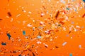 falling gold glitter foil confetti, on orange background, holiday and festive fun concept Royalty Free Stock Photo