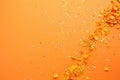 falling gold glitter foil confetti, on orange background, holiday and festive fun concept Royalty Free Stock Photo