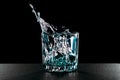 Falling ice cubes into a glass with gin. Glass with alcohol on a black background. Splashes of liquid Royalty Free Stock Photo