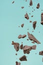 Falling pieces of dark chocolate on a light blue background, freezing in motion