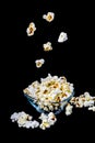 Falling popcorn on black background. Levitating popcorn around a ceramic bowl.