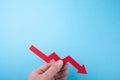 Falling red arrow down from the chart in hand on a blue background. Copy space Royalty Free Stock Photo