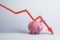 Falling red chart arrow with piggy bank on white background. Economic recession, losing savings concept. Royalty Free Stock Photo