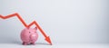 Falling red chart arrow with piggy bank on white background with mock up place. Royalty Free Stock Photo