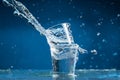 Falling small glasses and spilling water on a blue background