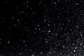 Falling  snow at night. Bokeh lights on black background, flying snowflakes in the air. Overlay texture. Snowstorm Royalty Free Stock Photo