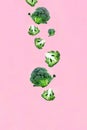 Falling soaring green broccoli slices on a pink background. Royalty Free Stock Photo