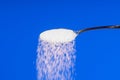 Falling sugar from a spoon on a blue background Royalty Free Stock Photo
