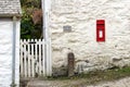 Falmouth, Cornwall, UK - April 12 2018: A traditional British Royal Mail Post Office post box, set into a rough rustic white wall