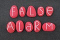 False Alarm Text Composed With Red Colored And Carved Stones Over Black Volcanic Sand