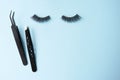 False eye lashes, black tweezers on blue background with copy space, mockup. Beauty concept - Tools for eyelash extension