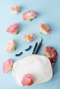 False eye lashes, black tweezers and pink flowers on blue background. Beauty concept - Tools for eyelash extension