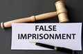 FALSE IMPRISONMENT - words on white paper on dark background with judge\'s gavel Royalty Free Stock Photo