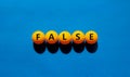 False symbol. Orange table tennis balls with the words `false`. Beautiful blue background, copy space. Warm sunshine. Business,