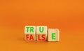 False or true symbol. Turned wooden cubes and changed the word false to true or vice versa. Beautiful orange table, orange Royalty Free Stock Photo