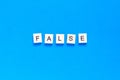 FALSE word alphabet letters on blue background. top view. flat layout Royalty Free Stock Photo