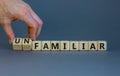 Familiar or unfamiliar symbol. Businessman turns wooden cubes changes the word unfamiliar to familiar. Beautiful grey table grey