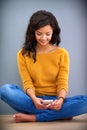 Familiarizing herself with the features of her new phone. a young woman sitting on the floor and using her mobile phone. Royalty Free Stock Photo