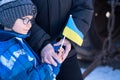 Families against war. Upset Ukrainian boy with his grandmom, with bue yellow flag, protesting war conflict. Evacuation of