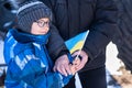 Families against war. Upset Ukrainian boy with his grandmom, with bue yellow flag, protesting war conflict. Evacuation of