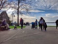 Families walking around with children and people sitting on benches, enjoying the view of Lake Washington on a bright sunny day