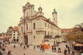 Families walking around market and 18th century Gothic style Heiliggeistkirche church