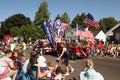 Families watch floats glide past at a fourth of July parade.