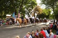 Families watch horses with riders walk past at a fourth of July parade.