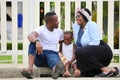 Family of African American people with young little daughter sitting in front of new house with white fence Royalty Free Stock Photo