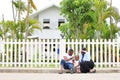 Family of African American people with young little daughter sitting in front of new house with white fence Royalty Free Stock Photo