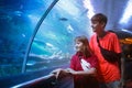 Family in aquarium. Kids watch fish, marine life