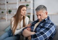 Family argument. Unhappy mature man sitting on sofa, his wife consoling him, trying to make peace after conflict at home Royalty Free Stock Photo