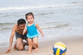 Family.Asian baby girl and father playing football on the beach. Royalty Free Stock Photo