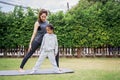 Family Asian Mother teacher training yoga child daughter on a yoga mat at home garden. Family outdoors. Parent with child spends