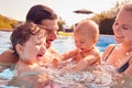 Family With Baby Daughter Having Fun On Summer Vacation Splashing In Outdoor Swimming Pool Royalty Free Stock Photo