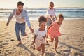 Family, beach and kids with parents running on sand on summer holiday. Mom, dad and children at ocean at sunset in Royalty Free Stock Photo