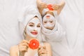 Family beauty treatment in the bathroom. Pretty mother and daughter baby girl make a clay mask for face skin, lying on