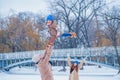 Family have fun on a frozen lake in the park against the background of the bridge Royalty Free Stock Photo