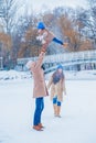 Family have fun on a frozen lake in the park against the background of the bridge Royalty Free Stock Photo