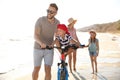 Happy family with bicycle on sandy beach near sea