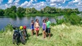 Family on bikes cycling outdoors, active parents and kids on bicycles, aerial top view of happy family with children near river