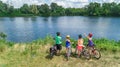 Family on bikes cycling outdoors, active parents and kids on bicycles, aerial view of happy family with children relaxing